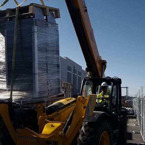 Mobile crane lifting wrapped solar structure component for installation